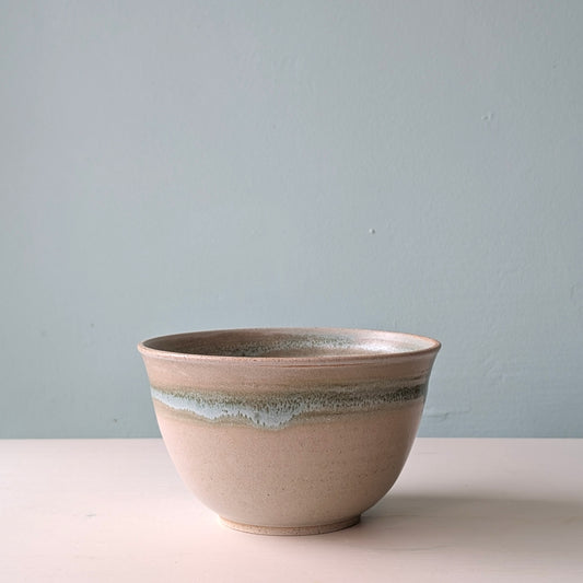 Front view of a beige and green ceramic salad bowl on a white background.