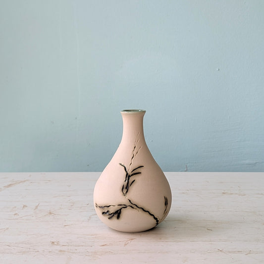 Ceramic vase with green seagrass pattern on a light wooden surface and blue background