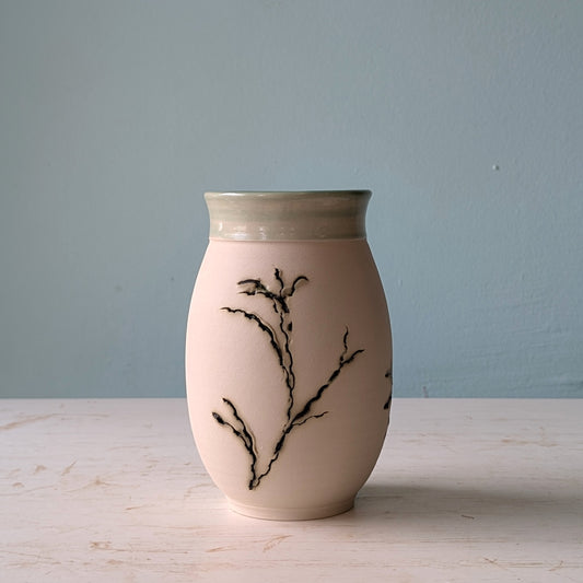 Ceramic vase with green seagrass patterns on a light surface with a blue background