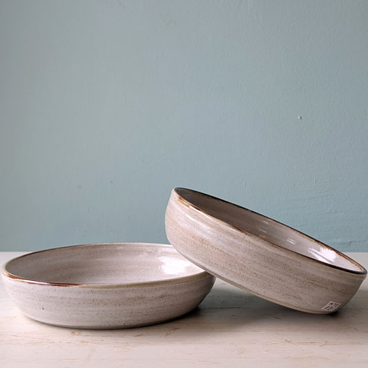 Two ceramic bowls on a light surface with a light blue background