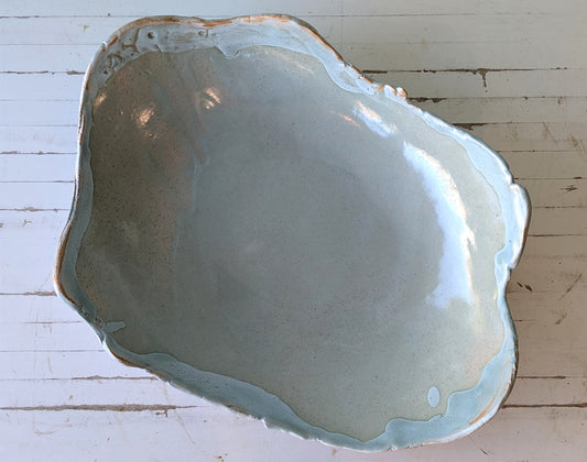 hand built ceramic platter with light blue glaze rim, viewed from above