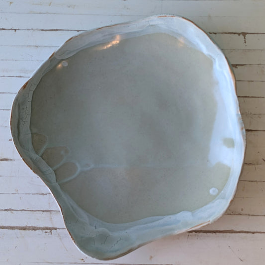 Hand built ceramic platter with light blue glaze rim, viewed from above