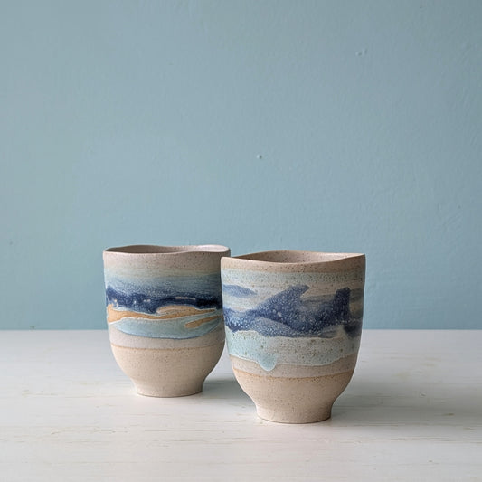 Two beige ceramic cups with dark blue glaze