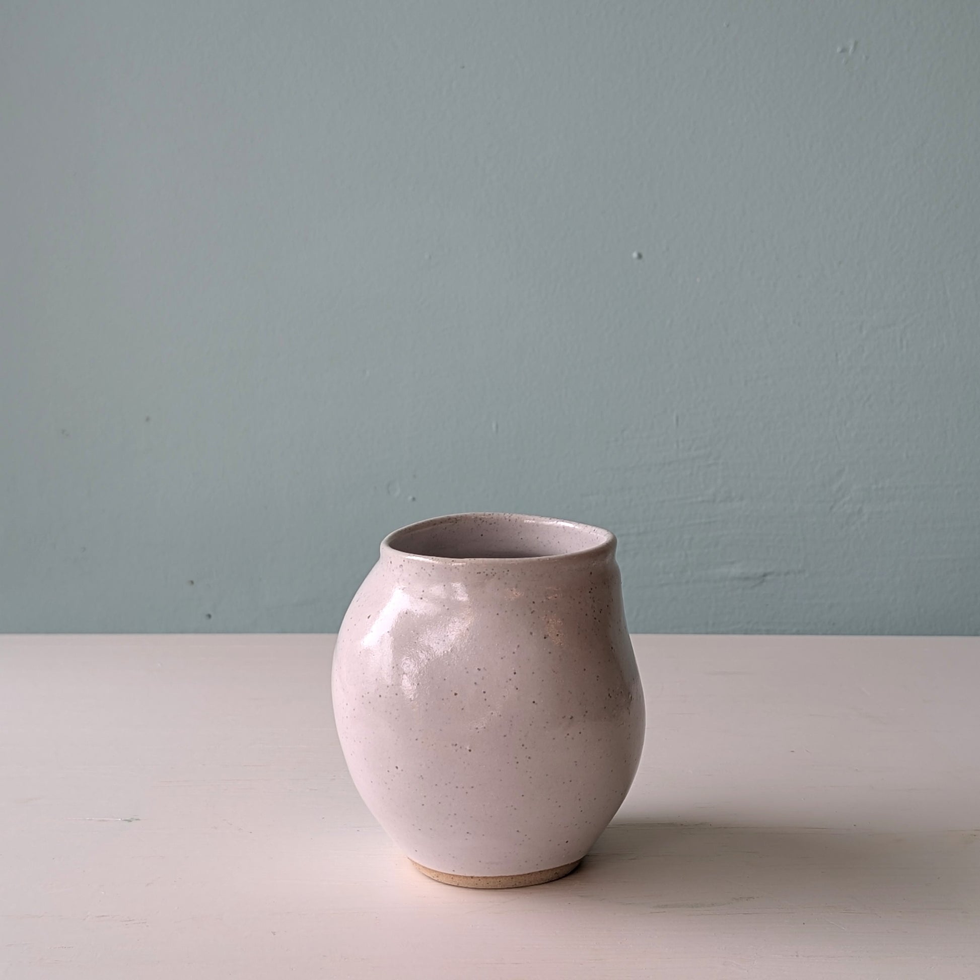 Ceramic vase on a white surface with a light blue wall background