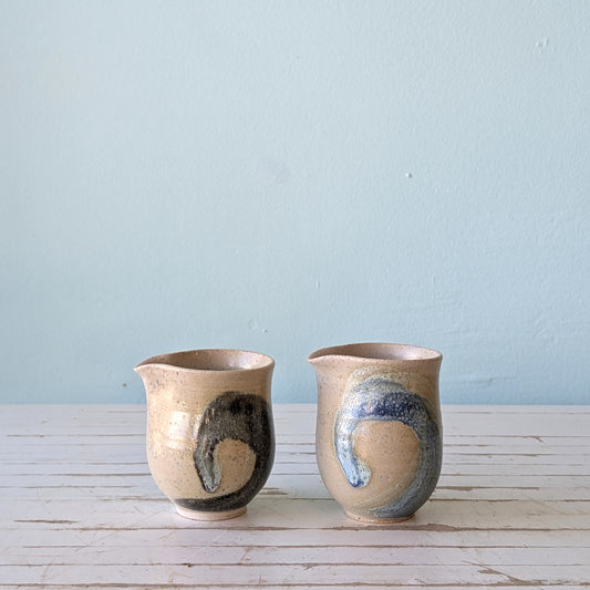 two ceramic milk jugs with blue swirl pattern