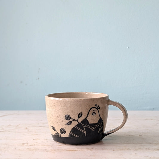 Ceramic mug with a black illustration of a peacock on a light blue background