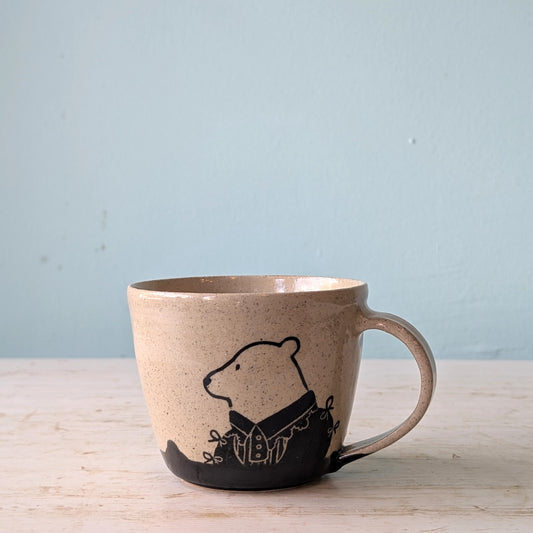Ceramic mug with a bear design on a wooden surface and light blue background