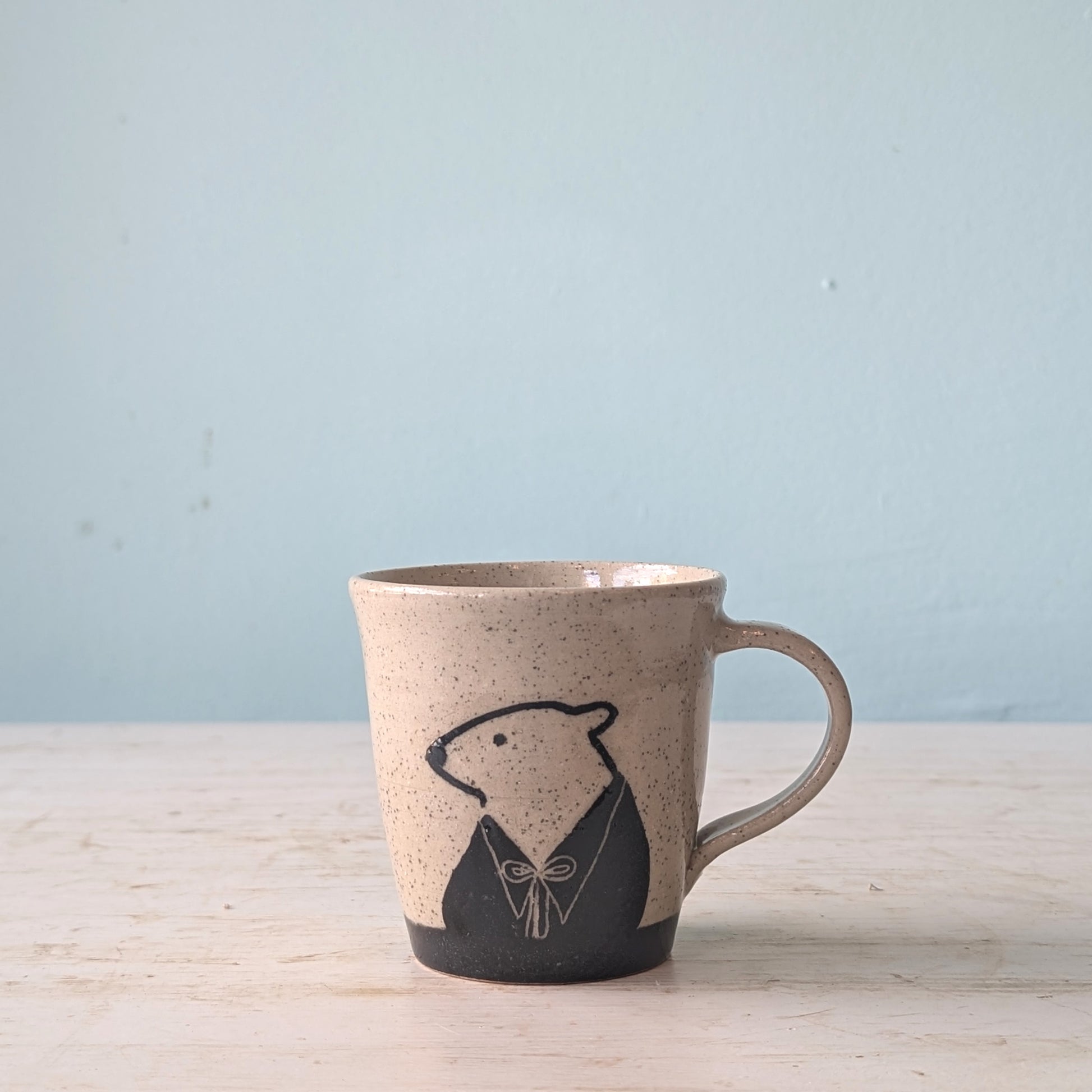 Ceramic mug with bear design on a light wooden surface and blue background