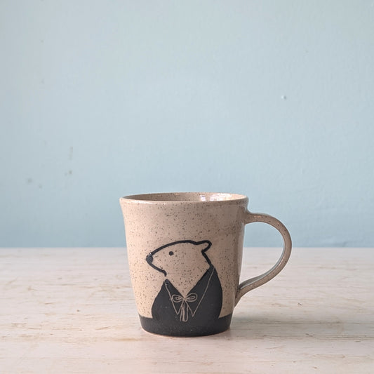 Ceramic mug with bear design on a light wooden surface and blue background