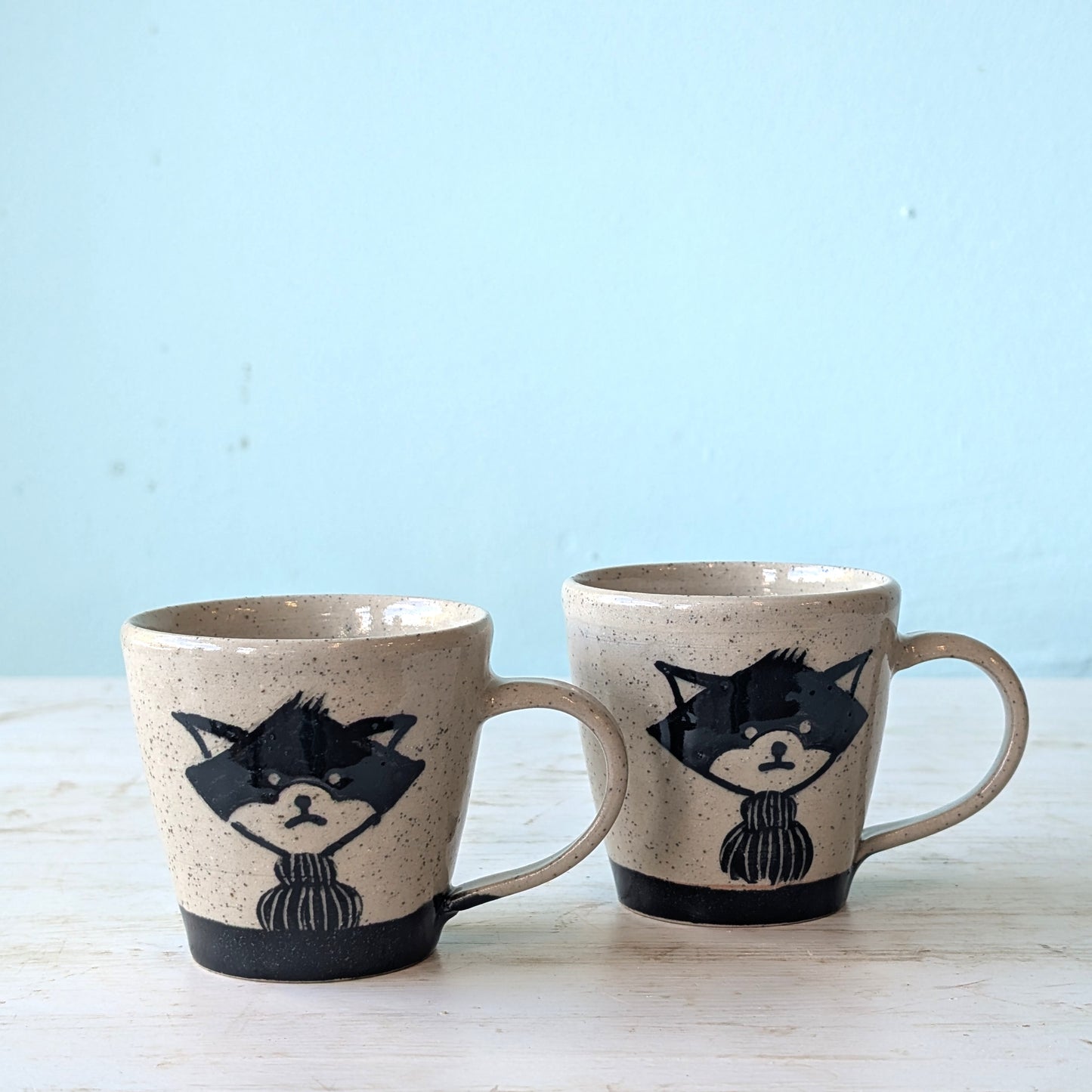 Two ceramic mugs with wolf illustrations on a light blue background