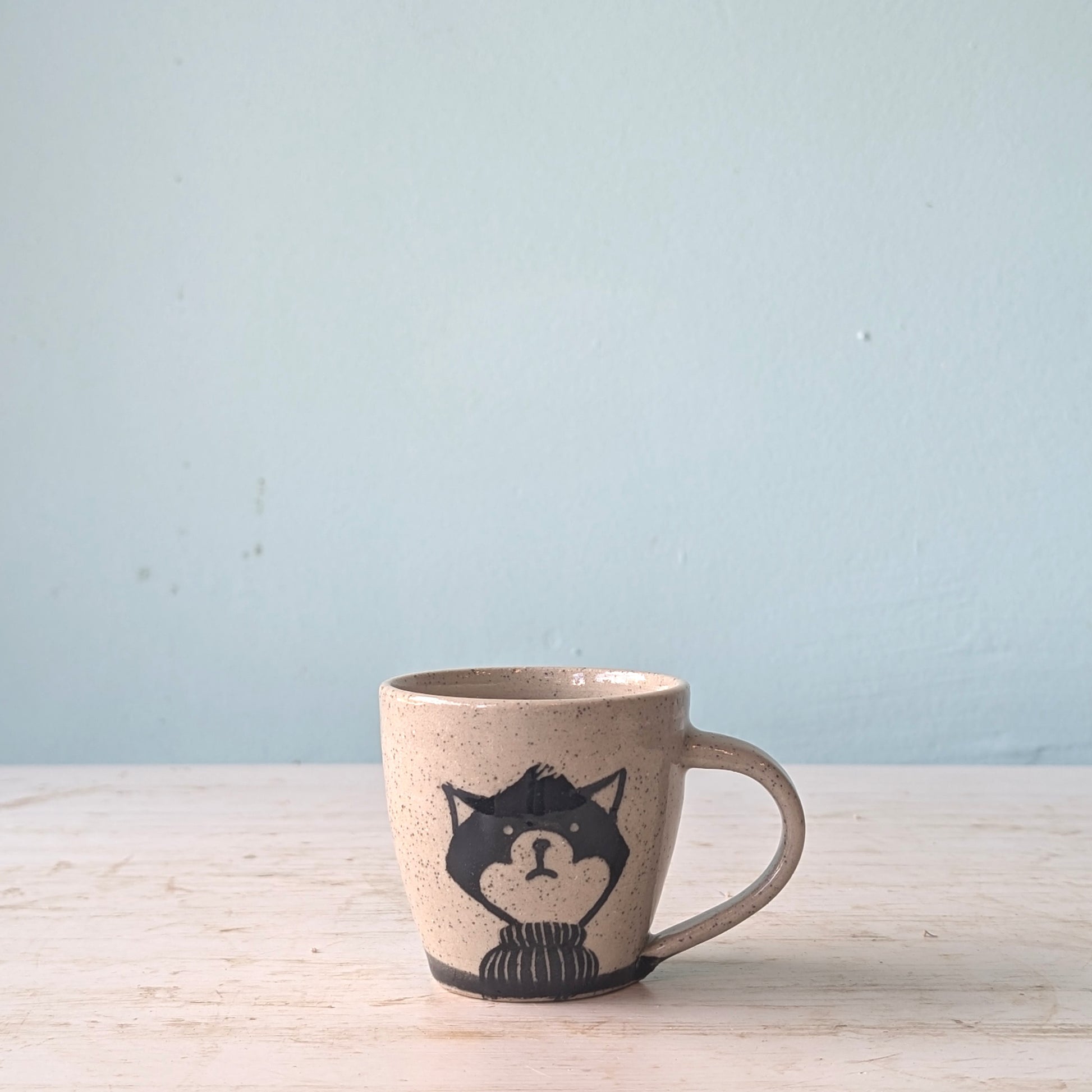 Ceramic mug with a wolf design on a light wooden surface and blue background
