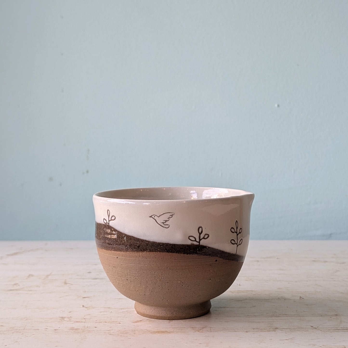 Ceramic bowl with decorative elements on a light wooden surface and blue background