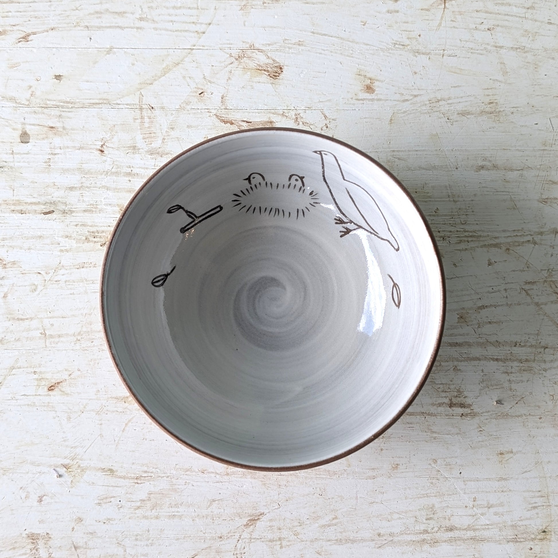 Ceramic bowl with bird design on a wooden surface