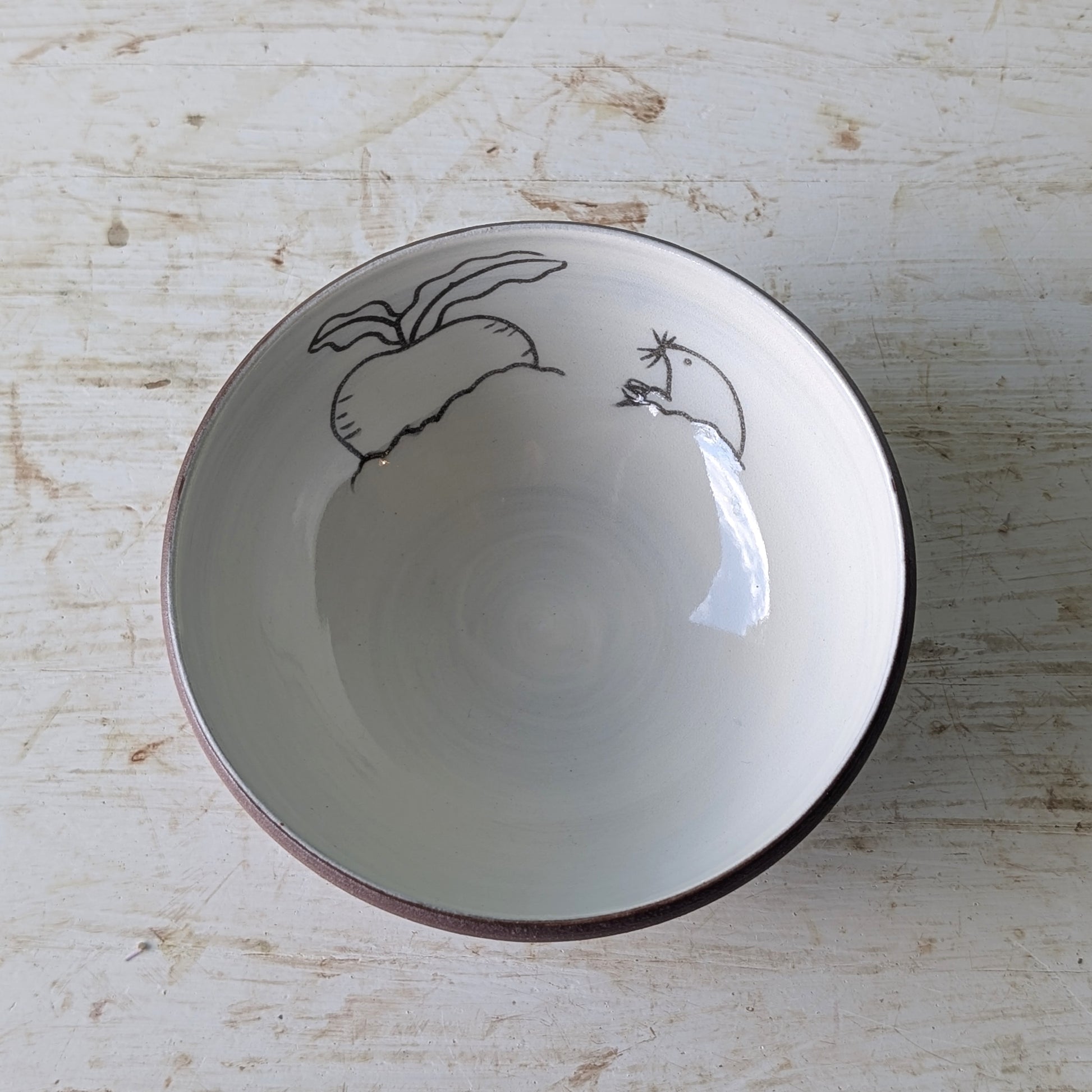 White ceramic bowl with black line art on a light wooden surface