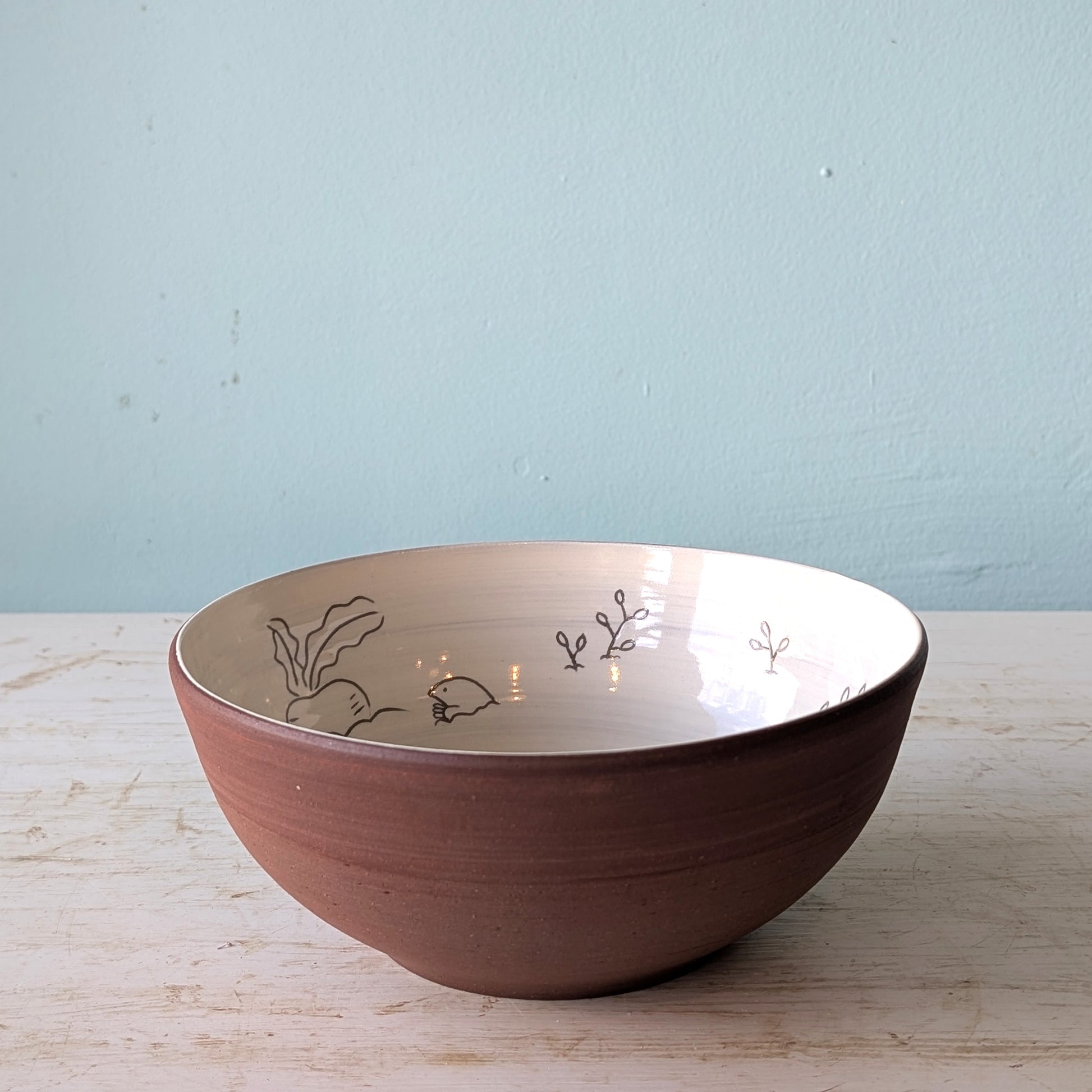 Ceramic bowl with floral patterns on a wooden surface and light blue wall background