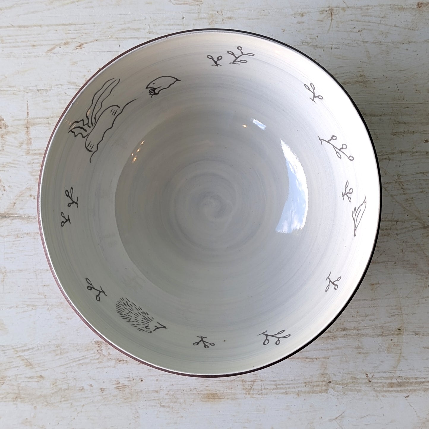 White ceramic bowl with carved floral patterns on a light wooden surface