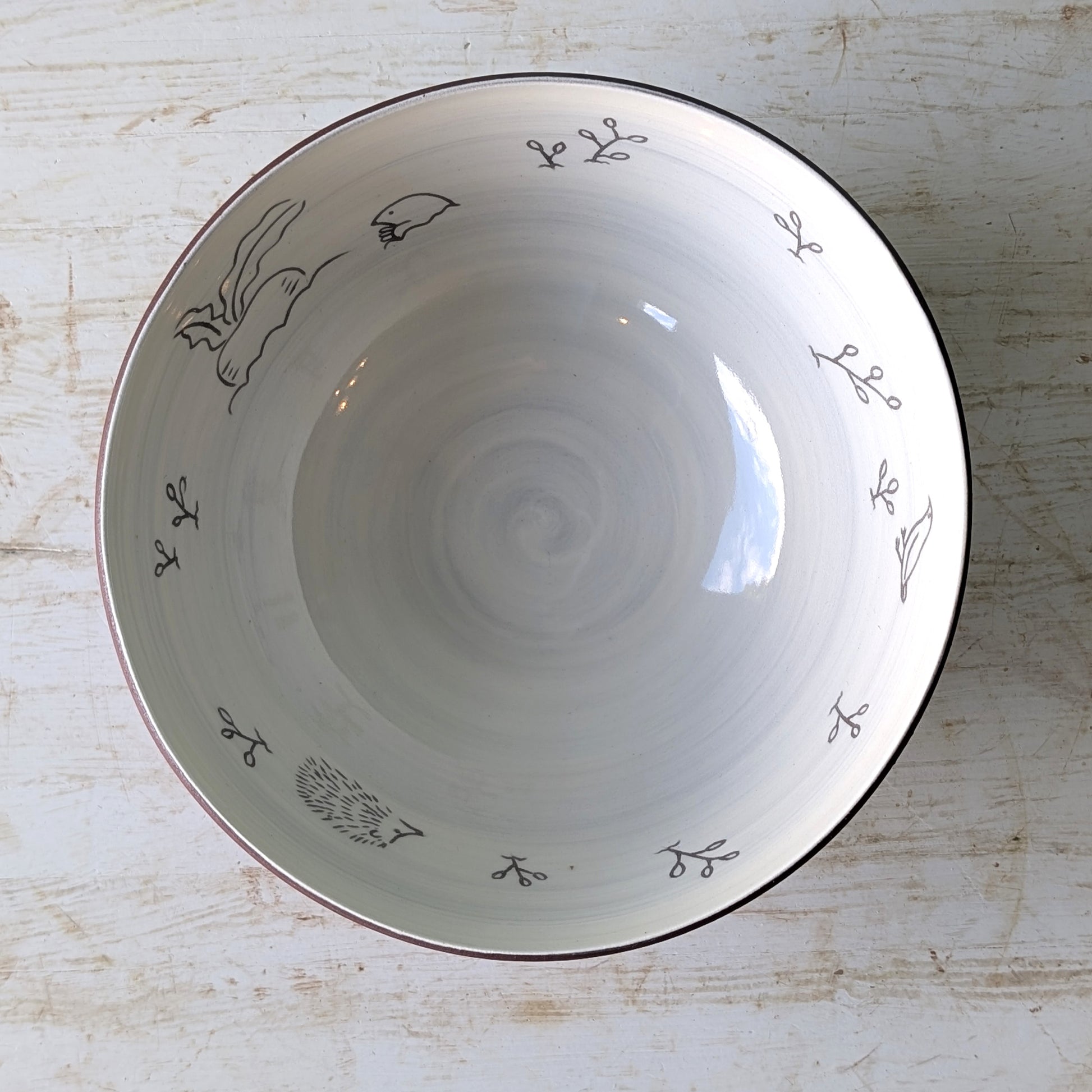 White ceramic bowl with carved floral patterns on a light wooden surface