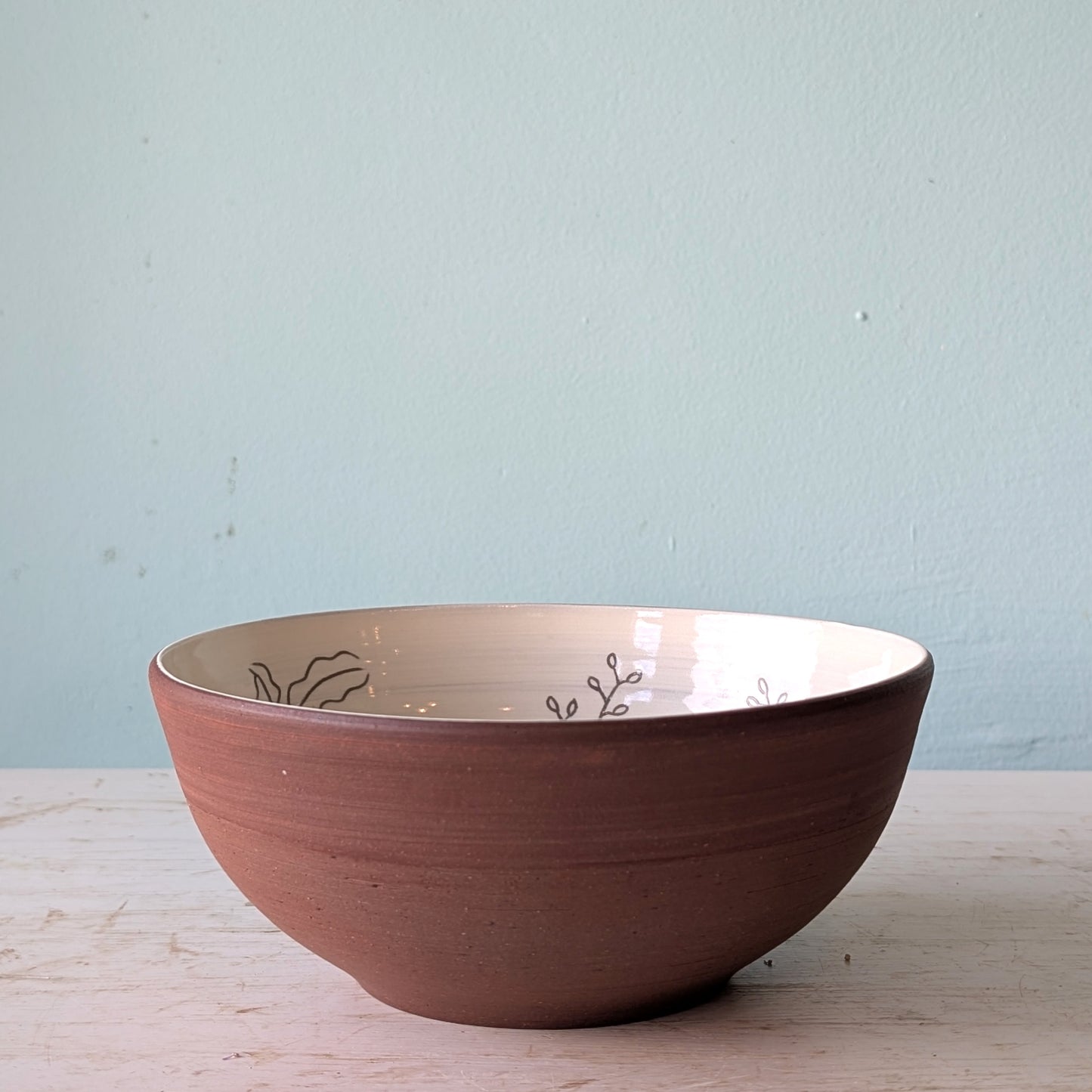 Ceramic bowl with decorative patterns on a light wooden surface and light blue wall background