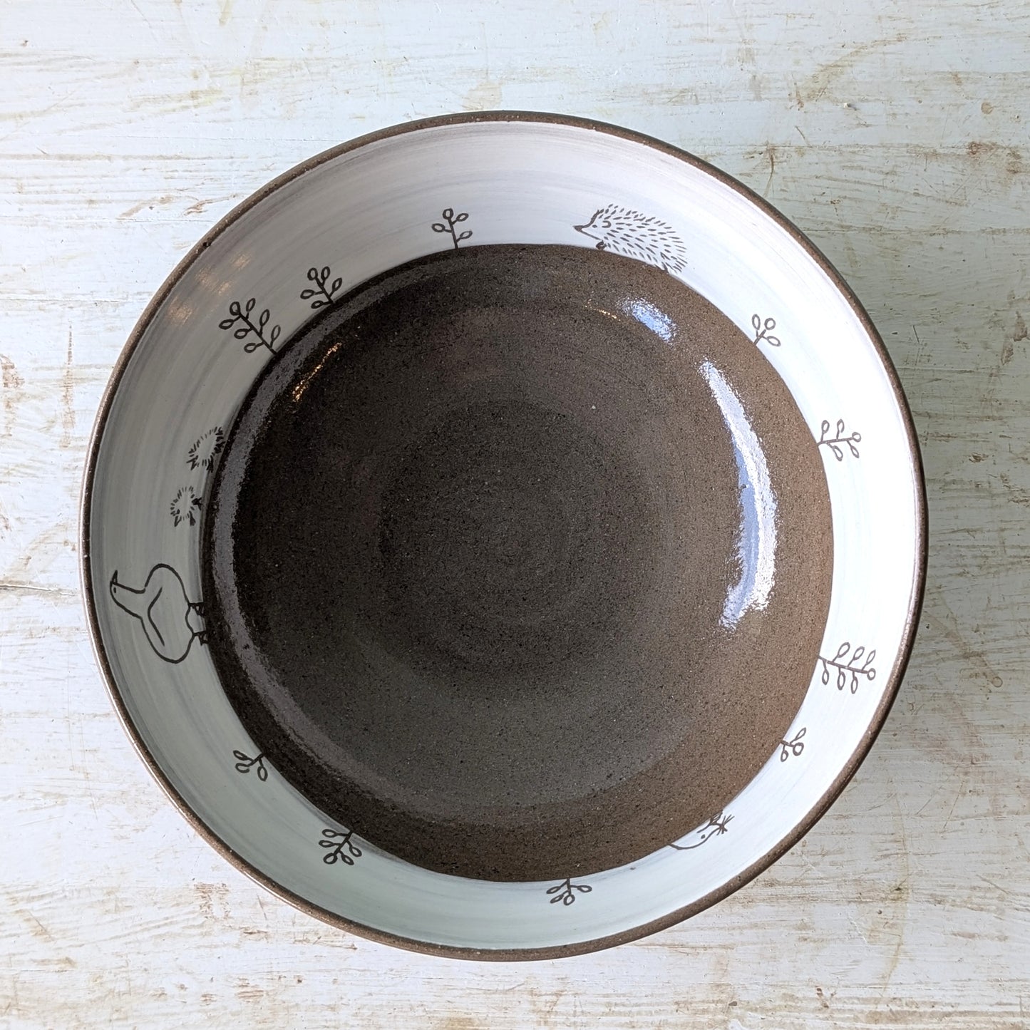 Ceramic bowl with decorative rim on a light wooden surface
