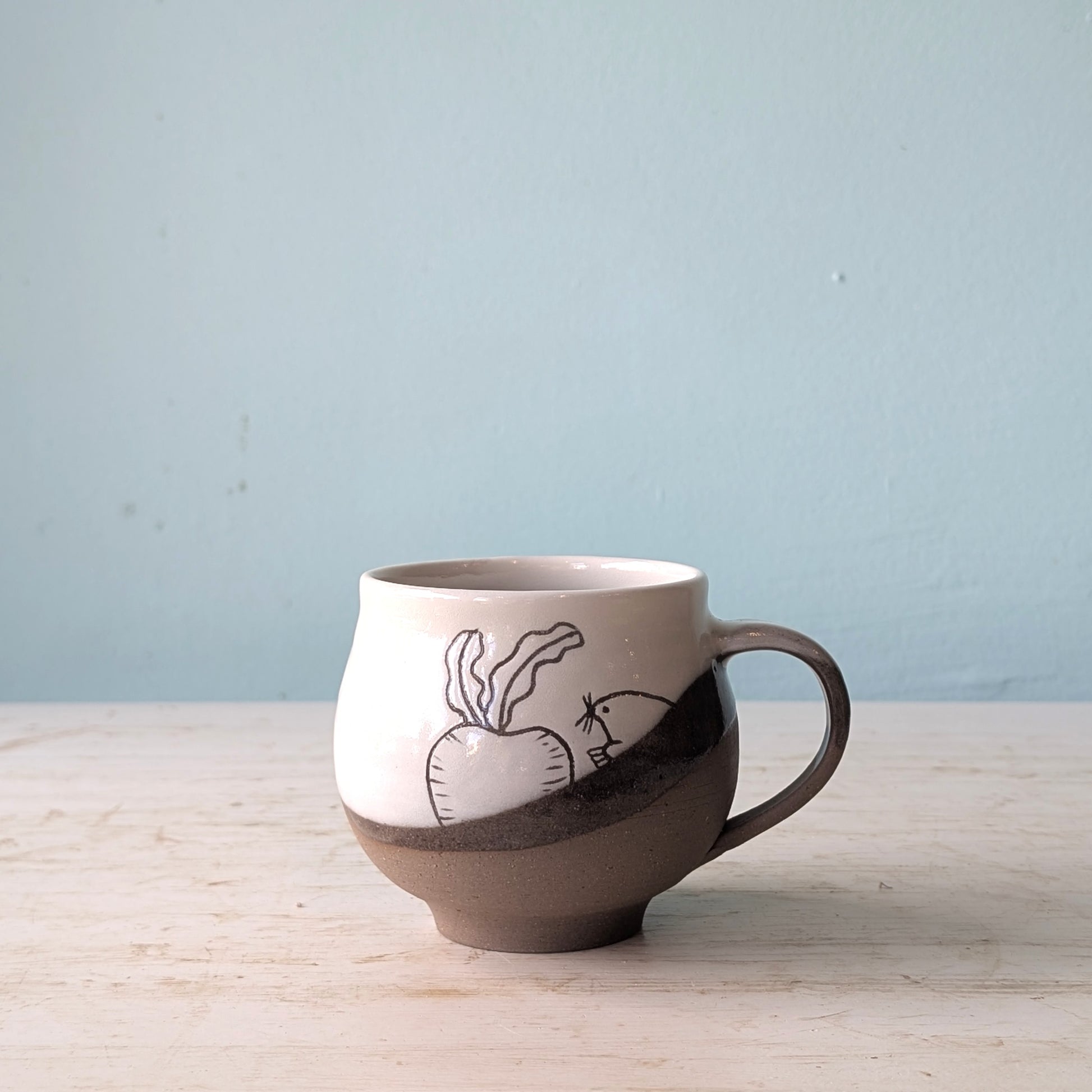 Ceramic mug with a handle on a wooden surface against a light blue background